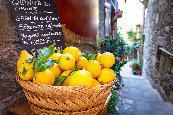 Korb voller Zitronen vor kleiner Gasse in Corniglia.