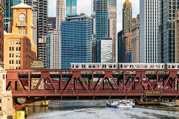 Hochbahn über Fluss vor Wolkenkratzern.