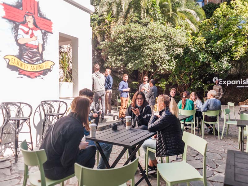 I partecipanti siedono nell'area esterna della scuola di lingue Expanish Buenos Aires e conversano tra loro.