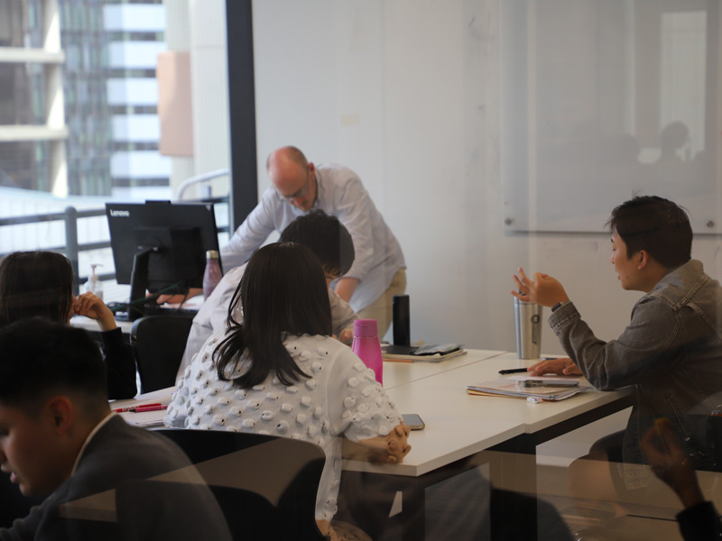 Englischunterricht in kleiner Gruppe, Lehrkraft unterstützt Lernende während einer Sprachreise in Adelaide.