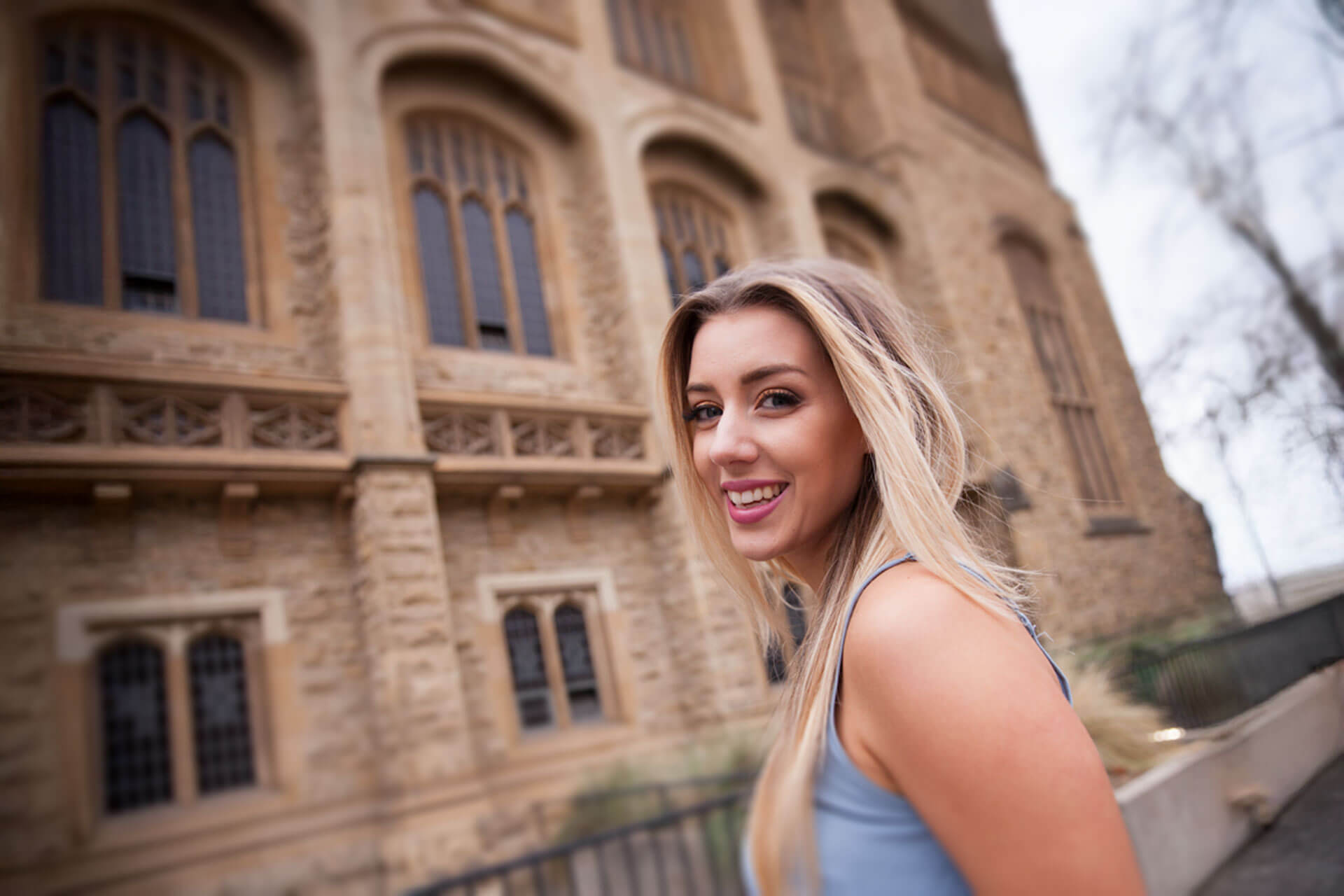 Teilnehmerin einer Sprachreise spaziert lächelnd an einem historischen Gebäude entlang und entdeckt die Umgebung ihres Englischkurses im Ausland.