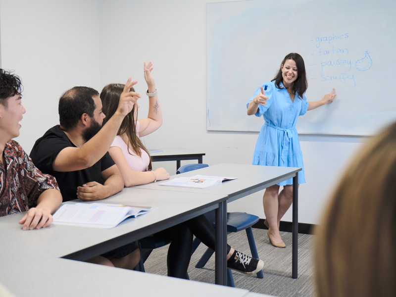 Lehrerin unterrichtet eine kleine Gruppe motivierter Sprachschülerinnen und Sprachschüler