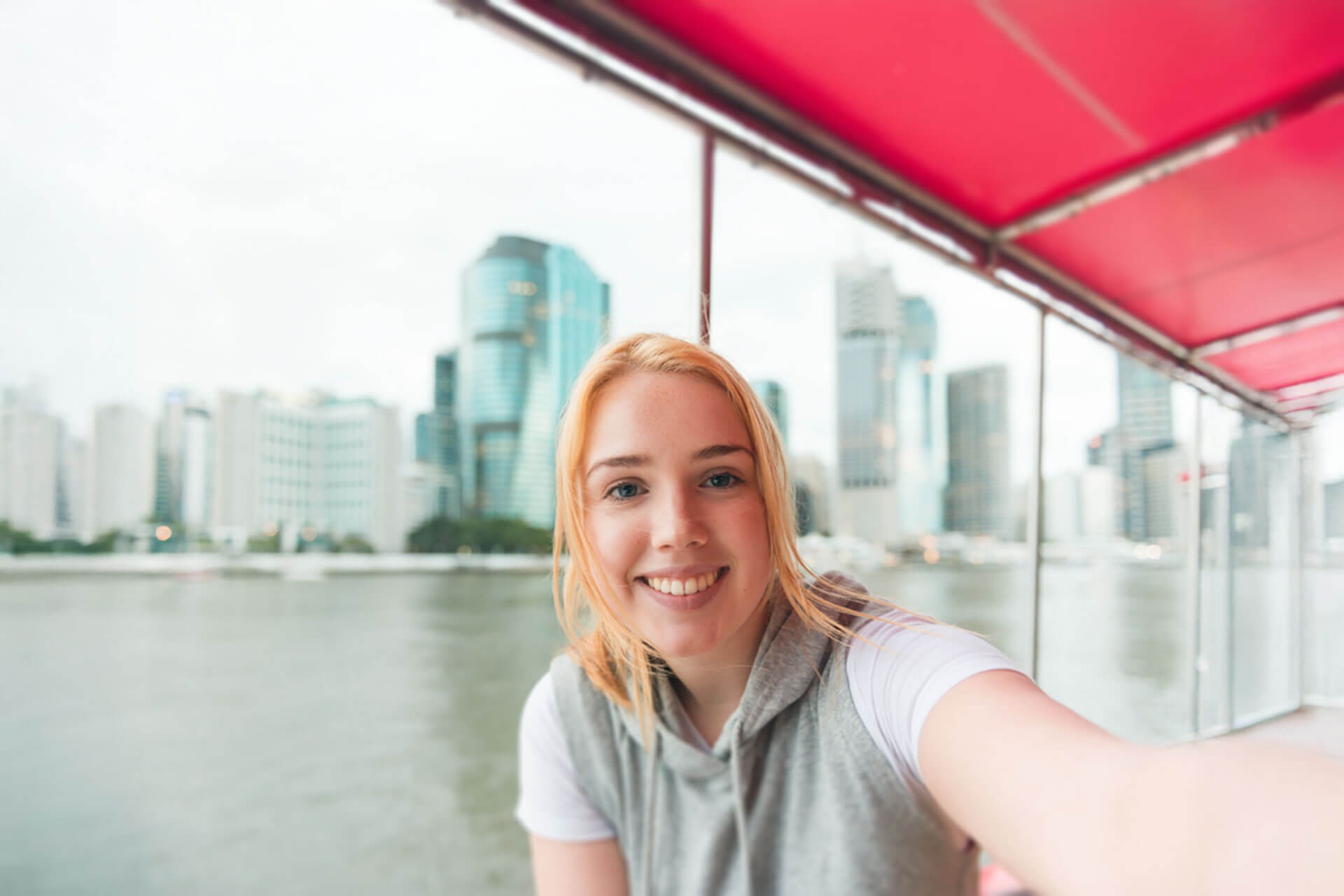 Teilnehmerin einer Englisch Sprachreise in Brisbane genießt Bootsfahrt mit Blick auf die Skyline