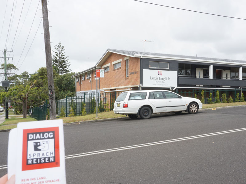 Außenansicht der Lexis English Sprachschule in Byron Bay mit Dialog Sprachreisen Broschüre