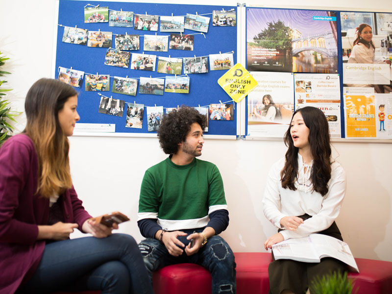 Drei internationale Sprachlernende unterhalten sich im Aufenthaltsbereich der Discover English Schule