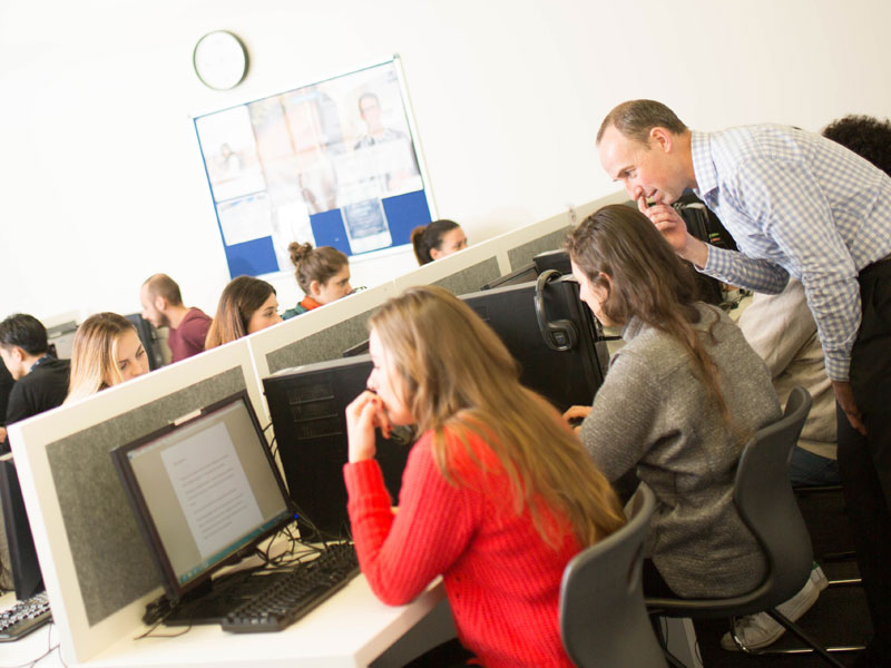 Lehrkraft unterstützt Lernende im Computerraum der Discover English Schule in Melbourne