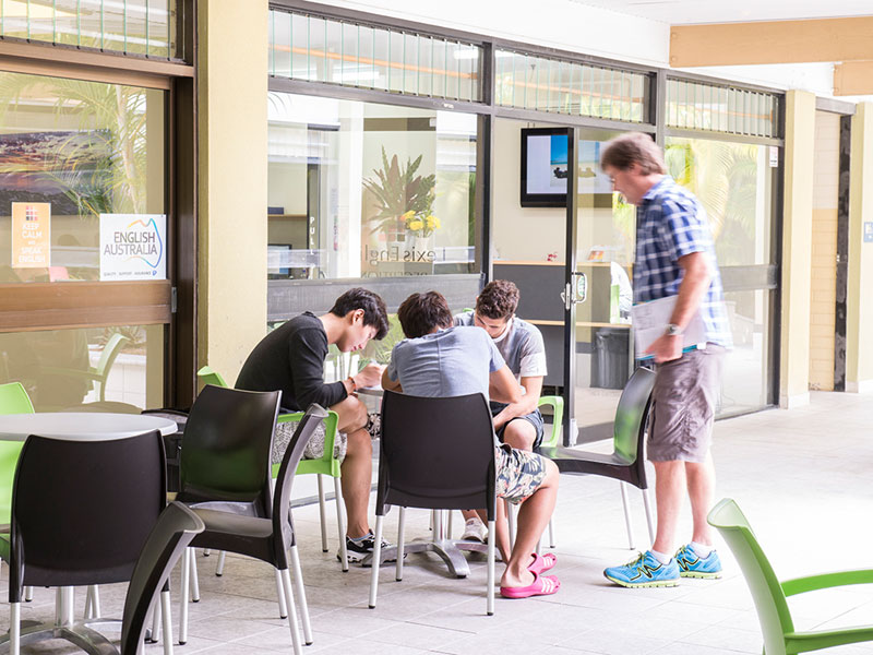 Lernende sitzen im Innenhof der Sprachschule und üben Konversation