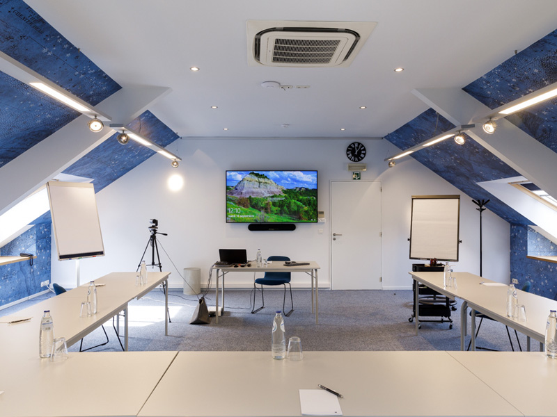 Moderner Seminarraum mit Präsentationsfläche und Gruppenarbeitsplätzen für intensive Business-Sprachtrainings.