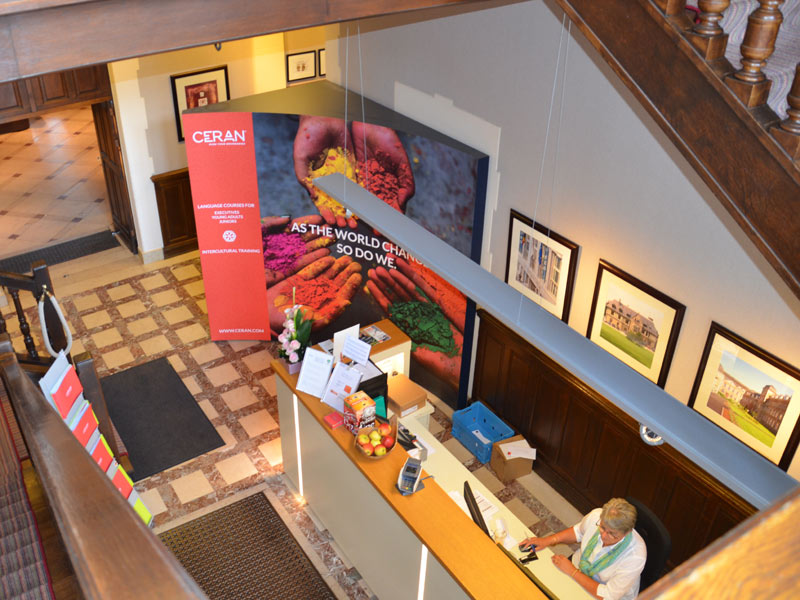Rezeption der CERAN Sprachschule Spa mit Infostand und Treppenaufgang