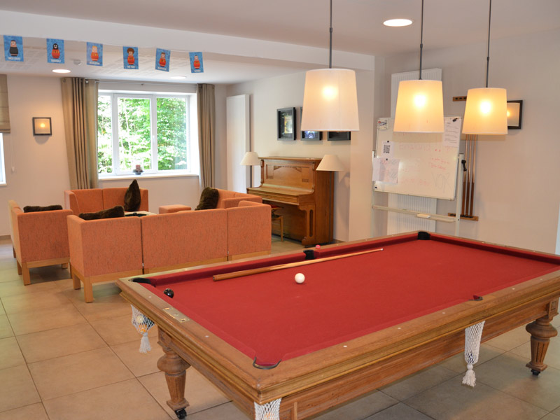 Gemütlicher Aufenthaltsraum mit Billardtisch, Sofaecke und Klavier