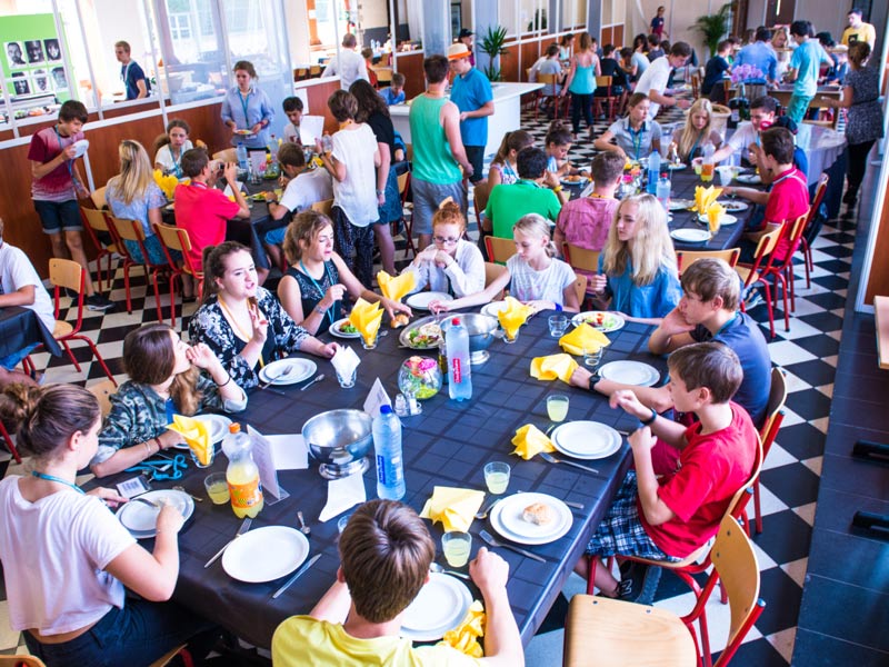 Jugendliche essen gemeinsam im Speisesaal der Sprachschule mit lebhafter Atmosphäre