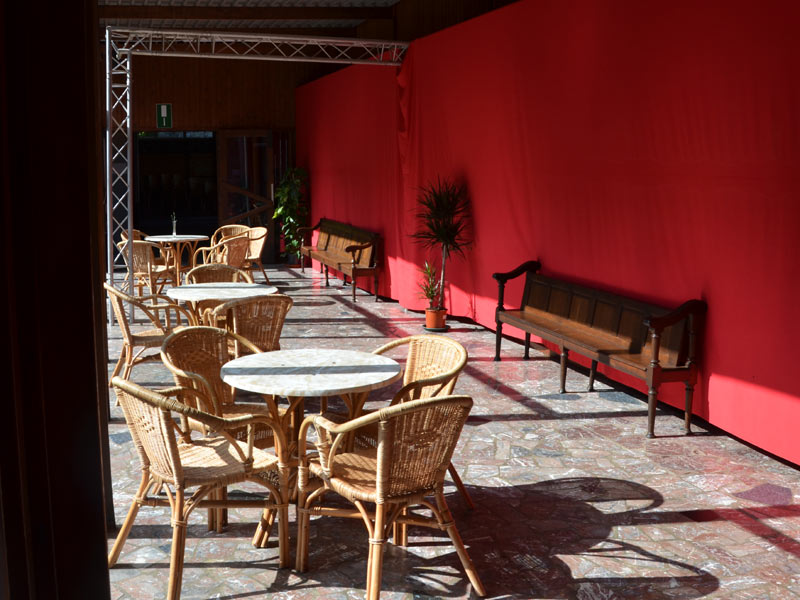 Sitzbereich mit Rattanmöbeln und roten Wänden im Aufenthaltsraum der Schule