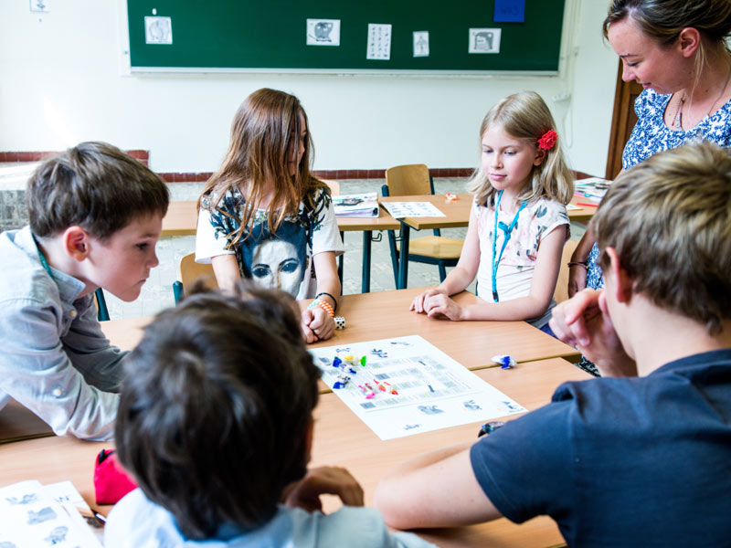 Kinder und Jugendliche arbeiten spielerisch im Klassenzimmer mit Lehrkraft an Sprachübungen