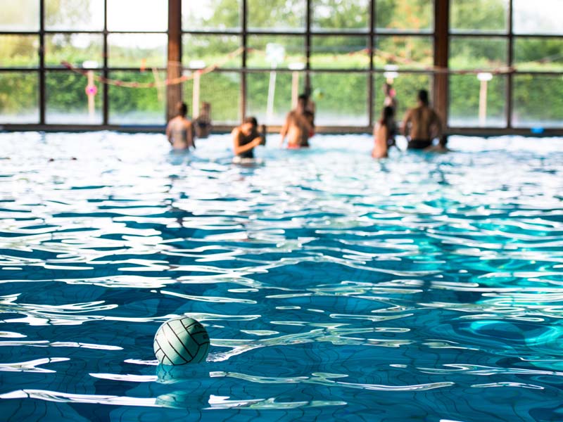 Teilnehmende beim Schwimmen und Wasserballspiel im Hallenbad der Schule