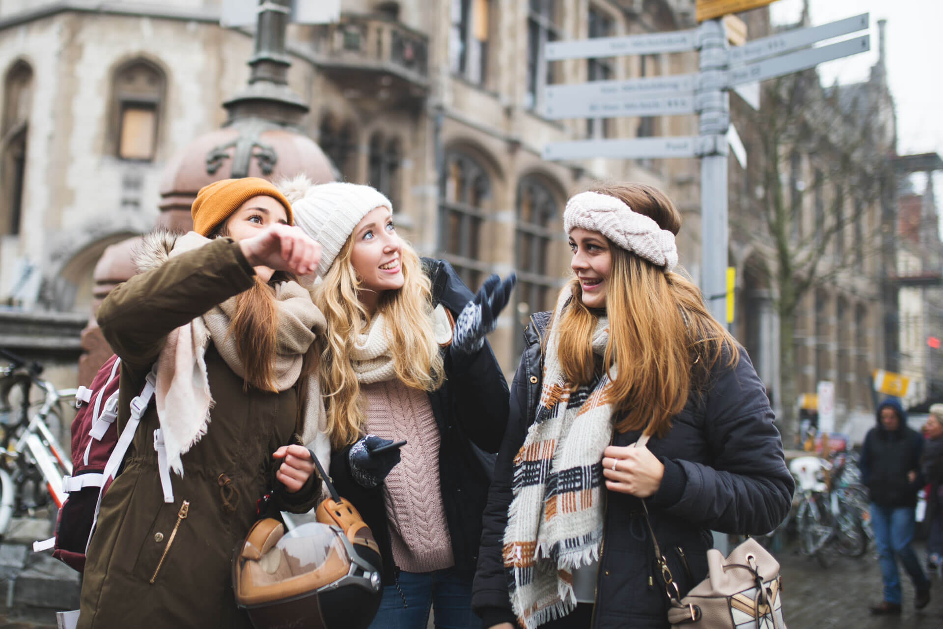 Drei Jugendliche mit Winterkleidung erkunden fröhlich eine Altstadt mit historischen Gebäuden