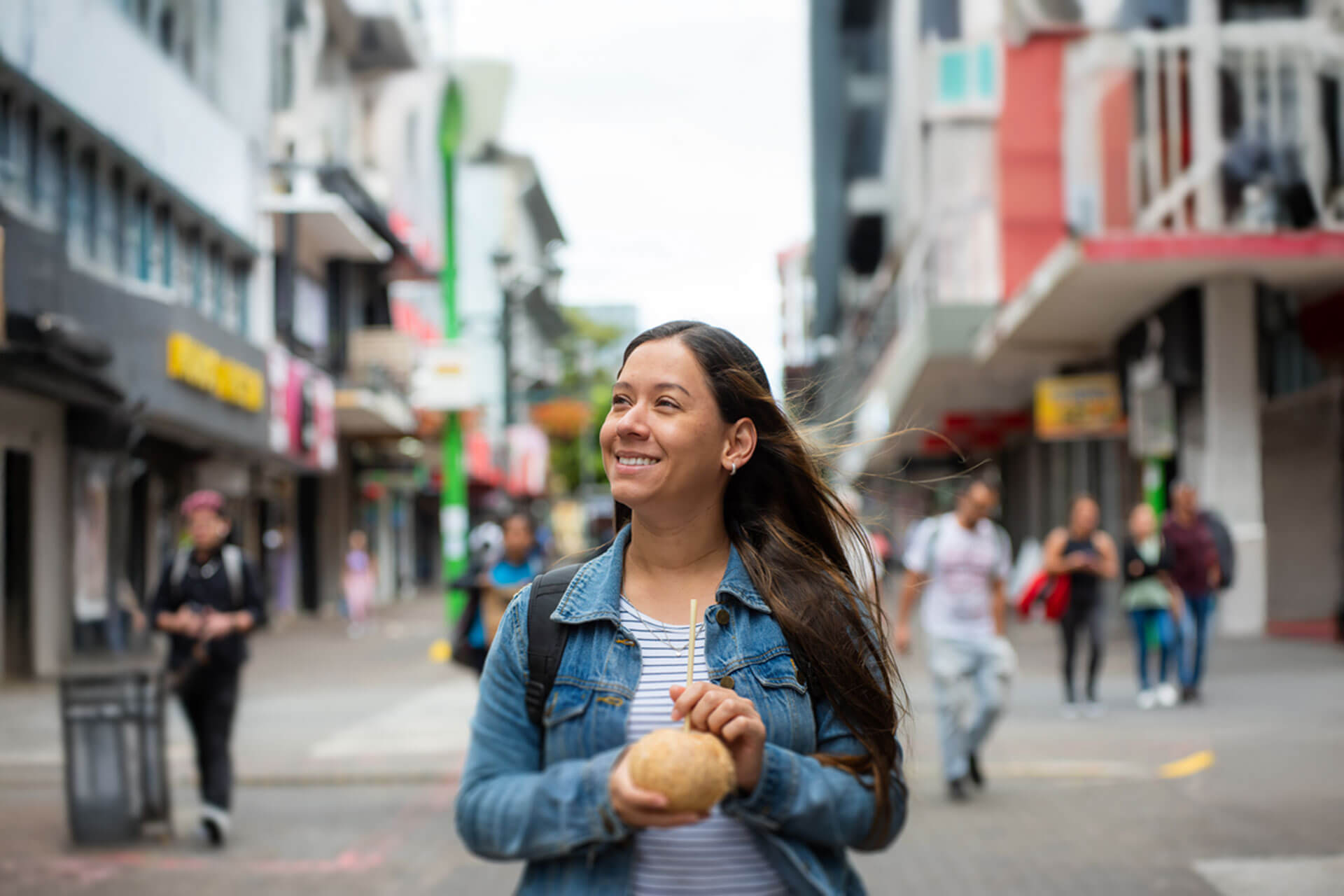 Teilnehmerin einer Sprachreise in San José genießt das Stadtleben mit einem Getränk aus einer frischen Kokosnuss