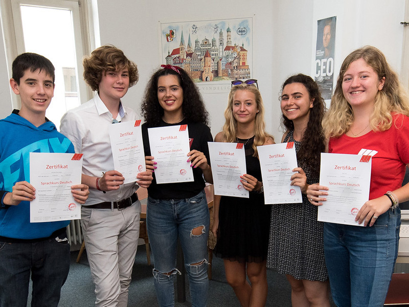 ugendliche halten stolz ihre Zertifikate nach Abschluss des Sprachkurses in Augsburg