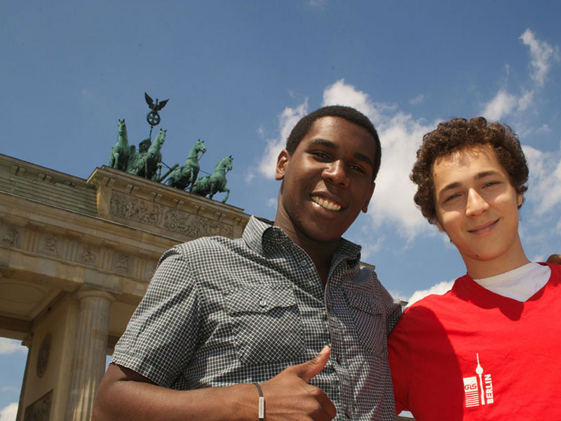 Zwei Sprachreisende posieren vor dem Brandenburger Tor während einer Deutsch-Sprachreise nach Berlin.