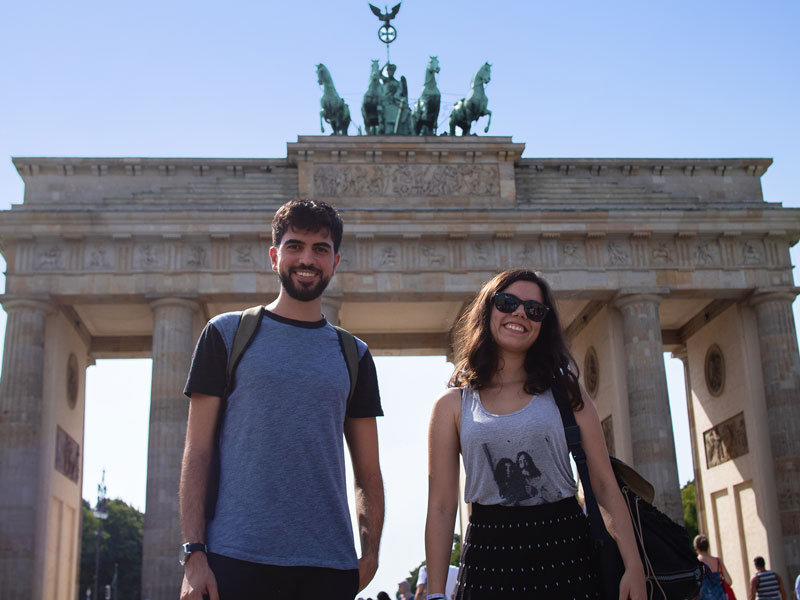 Zwei Sprachkursteilnehmende posieren vor dem Brandenburger Tor in Berlin