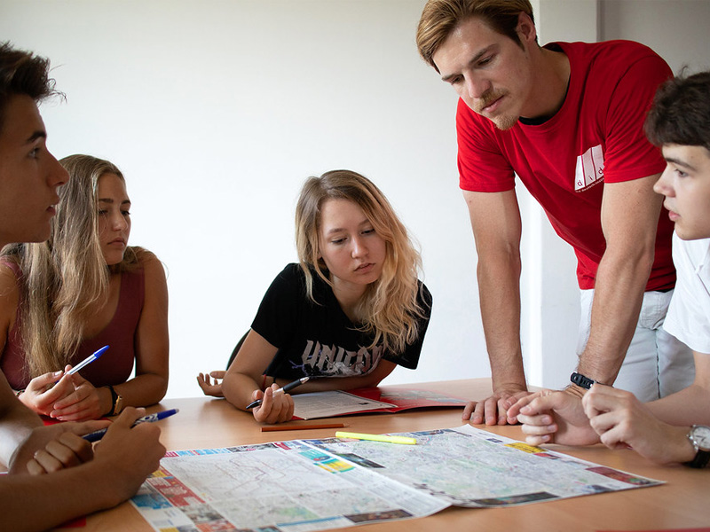 Kleingruppe Jugendlicher arbeitet gemeinsam mit Lehrkraft