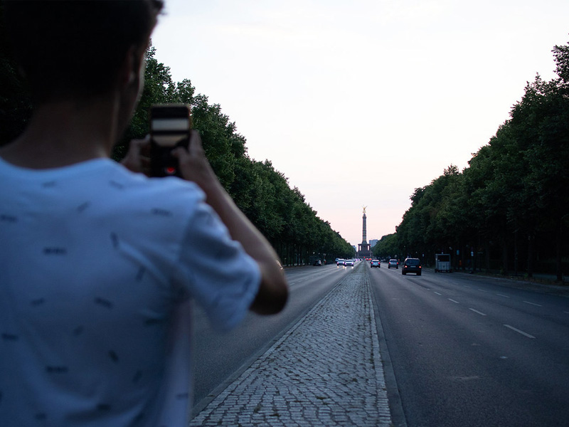 Jugendlicher fotografiert die Straße des 17. Juni mit Blick auf die Siegessäule in Berlin