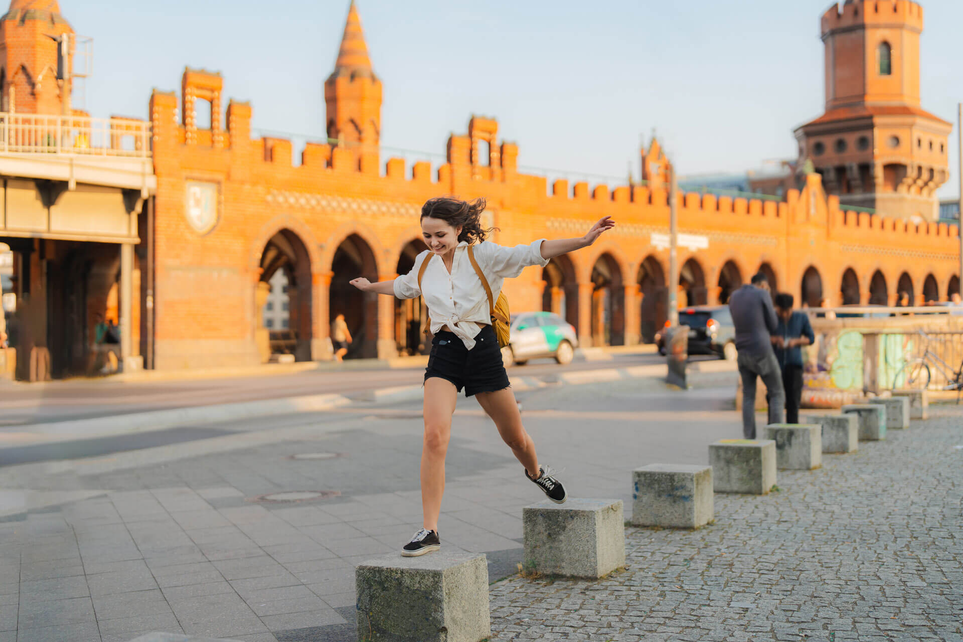 Junge Person springt spielerisch vor der Oberbaumbrücke in Berlin bei Sonnenuntergang