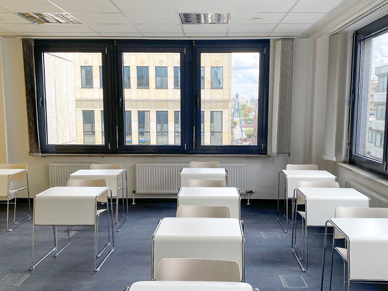 Heller Unterrichtsraum mit weißen Tischen und Blick auf die Frankfurter Innenstadt