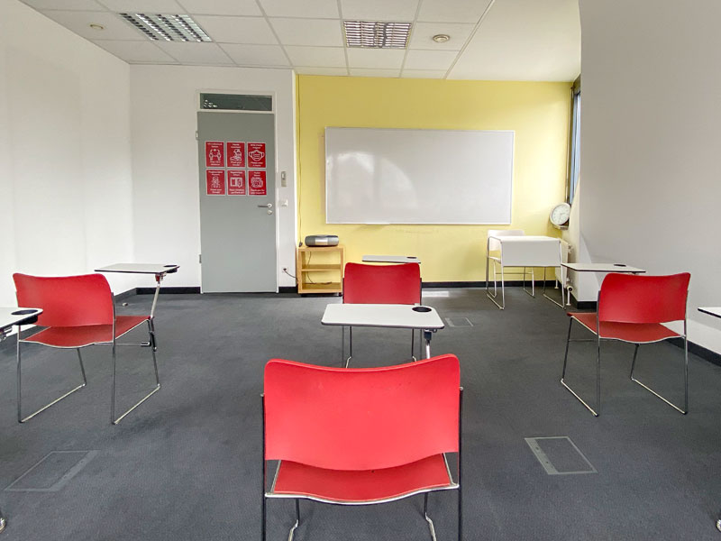 Klassenzimmer mit roten Stühlen und gelber Wand im did deutsch institut Frankfurt