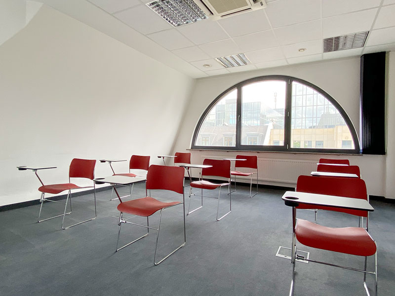 Heller Unterrichtsraum mit großen Bogenfenstern und modernen Sitzreihen in Frankfurt