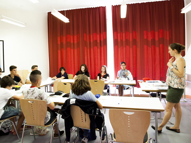 Unterrichtsszene mit Jugendlichen und Lehrkraft in modernem Klassenraum