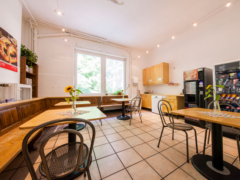 Gemütlicher Aufenthaltsraum mit Holzmöbeln und Snackautomaten in der Alpadia Sprachschule Freiburg