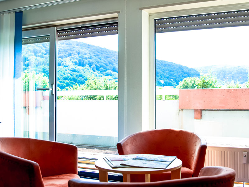 Loungebereich der OISE Sprachschule Heidelberg mit Panoramablick auf die grünen Hügel der Stadt 