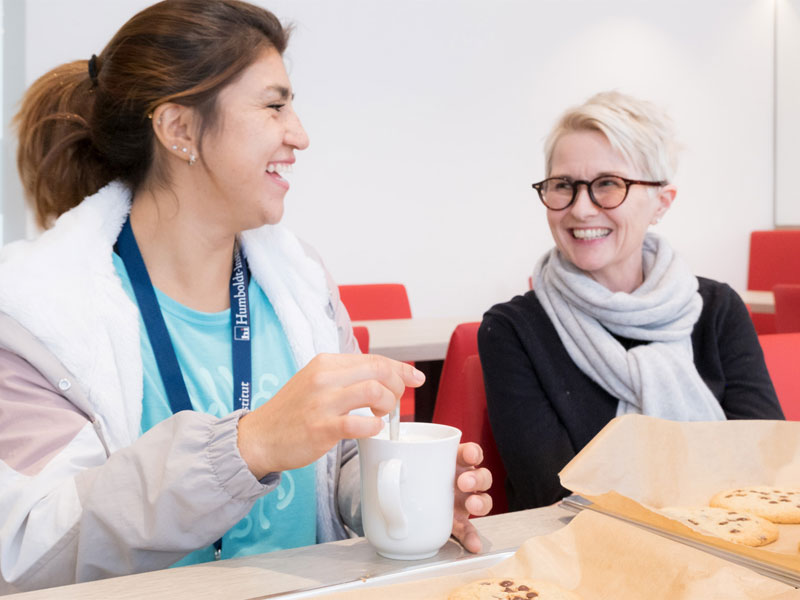 Zwei Personen unterhalten sich bei Kaffee und Keksen im Aufenthaltsraum des Humboldt-Instituts