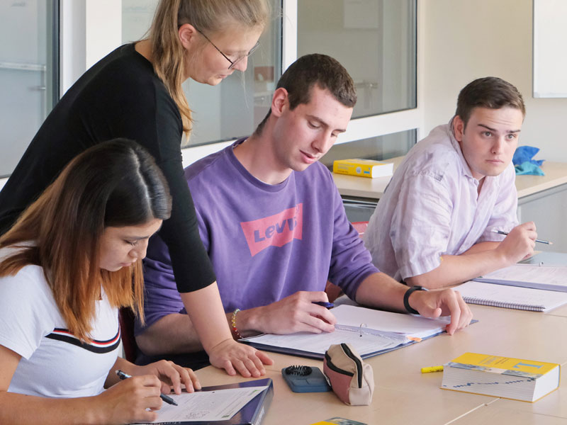 Lehrkraft unterstützt Kursteilnehmende individuell während einer Unterrichtseinheit