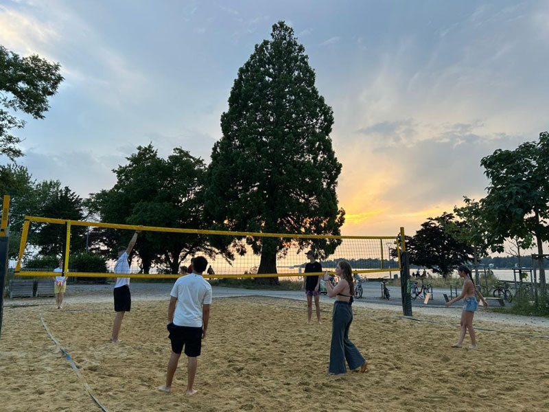Jugendliche spielen Beachvolleyball am Bodensee bei Sonnenuntergang