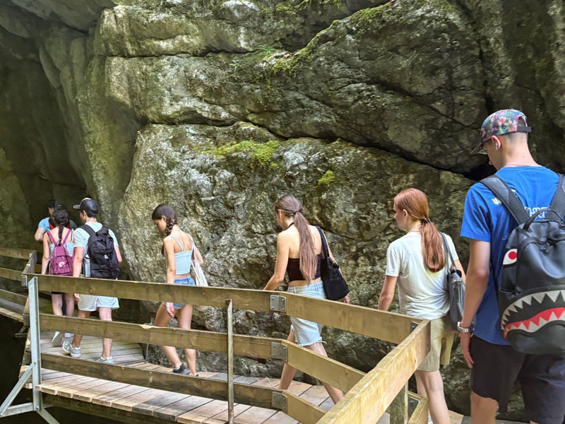 Gruppe junger Menschen erkundet eine Felsenschlucht auf einem Holzsteg