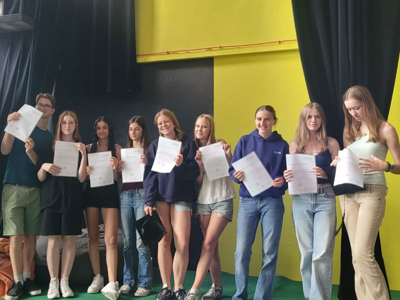 Teilnehmende der Sprachschule halten stolz ihre Teilnahmezertifikate hoch