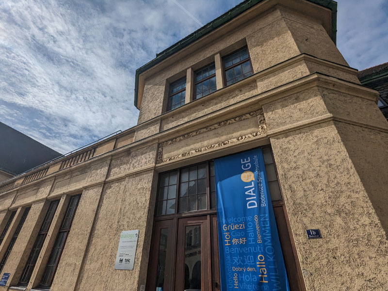 Eingang der Dialoge Sprachschule in Lindau mit blauem Banner und Begrüßung in verschiedenen Sprachen