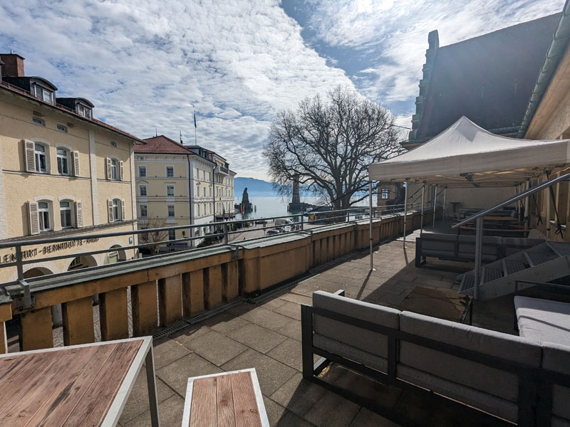 Schuleigene Terrasse mit Sitzgelegenheiten und Blick auf den Bodensee unter blauem Himmel