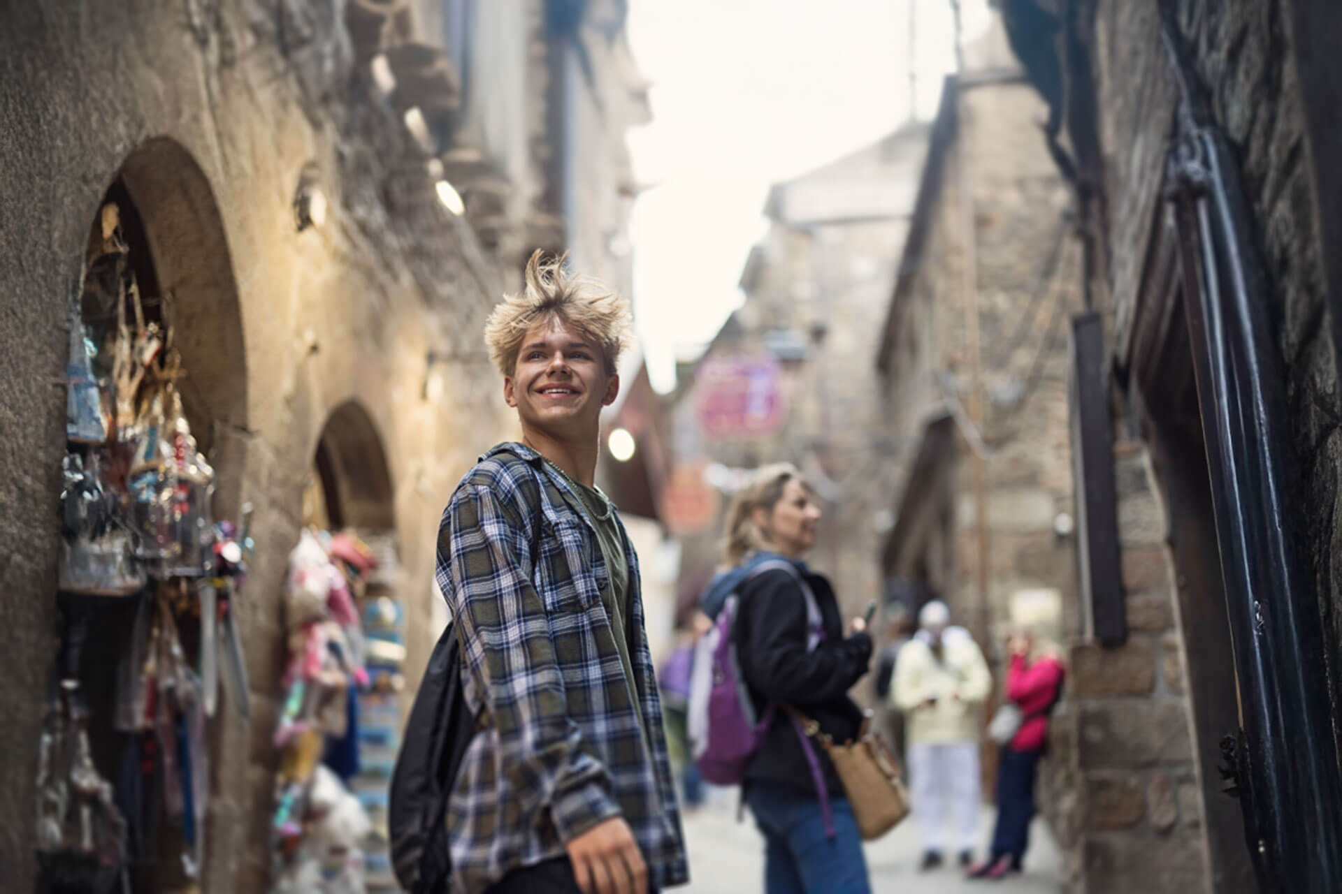 Jugendlicher mit Rucksack spaziert durch eine historische Altstadtgasse in Lindau und lächelt