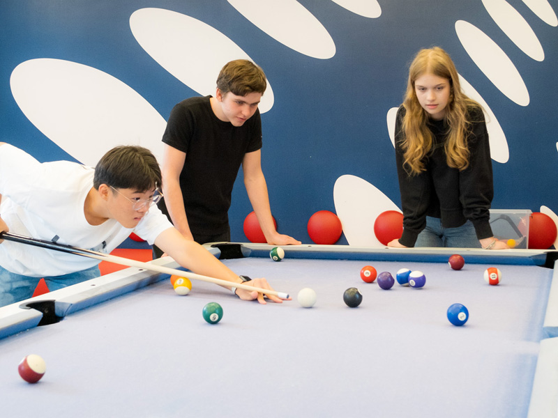 Drei Jugendliche spielen gemeinsam Billard in einem Freizeitraum
