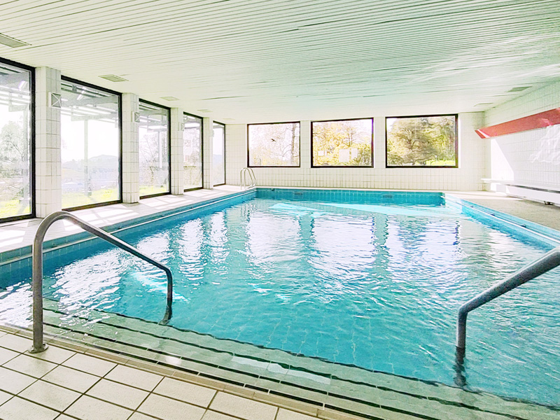 Helles Hallenbad mit großen Fenstern und Blick auf die umliegende Natur