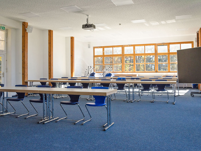 Moderner Klassenraum mit viel Tageslicht und blauen Stühlen im Humboldt-Institut Lindenberg