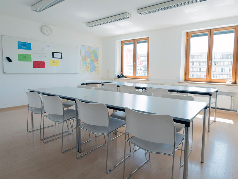 Moderner Klassenraum mit großen Fenstern und hellen Möbeln im did deutsch-institut München