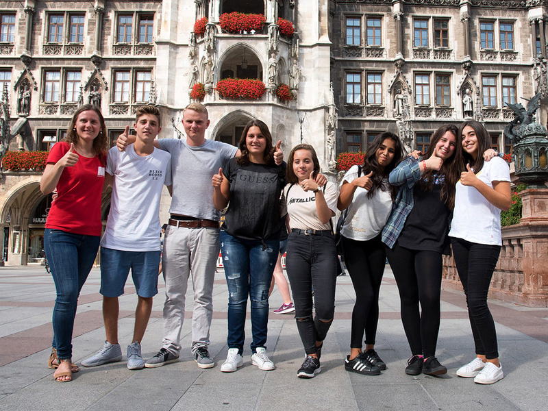Gruppe Jugendlicher steht lächelnd vor dem Münchener Rathaus am Marienplatz
