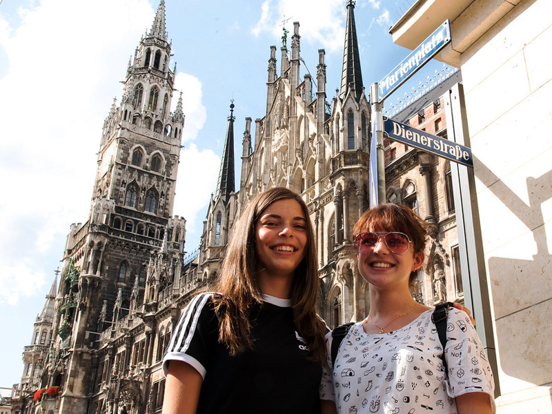 Zwei Jugendliche posieren lächelnd vor dem Neuen Rathaus am Marienplatz in München