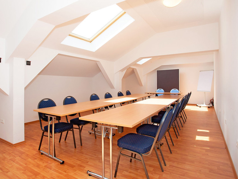 Heller Klassenraum mit großen Schrägfenstern und blauen Stühlen im did deutsch-institut München