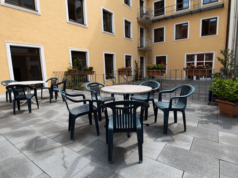 Sonnige Terrasse der Sprachschule in München mit Sitzgruppen und Blumen