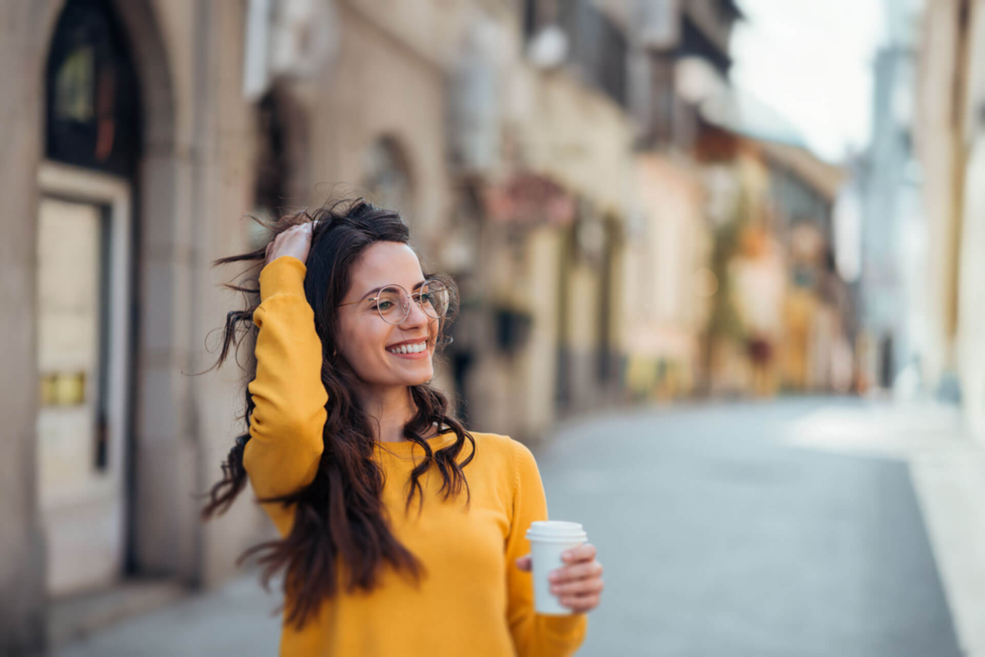 Person mit Kaffee in der Hand lächelt beim Spaziergang durch die Altstadt von München