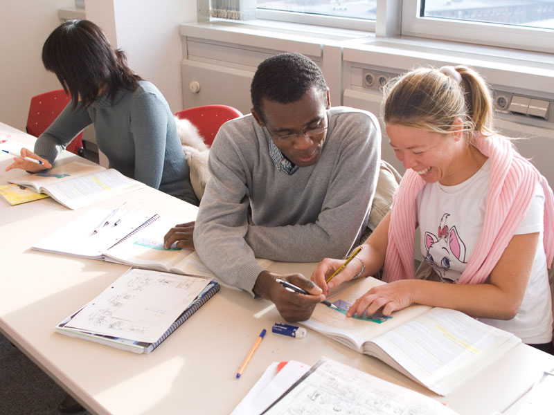 Zwei Lernende arbeiten konzentriert im Unterricht und helfen sich gegenseitig bei Aufgaben